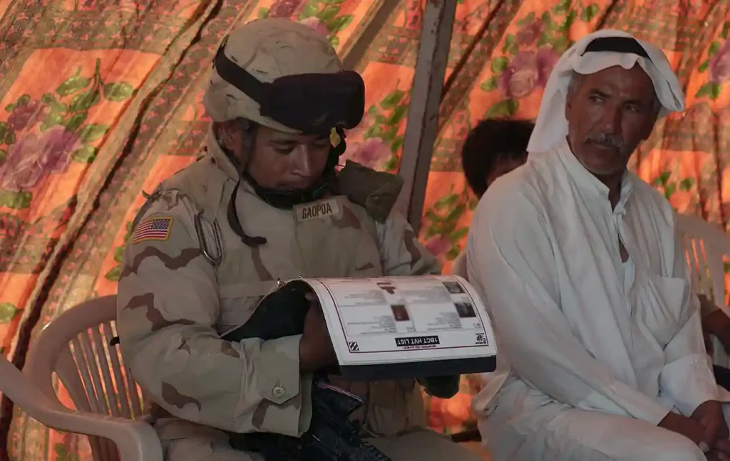 Sergeant Lale Gaopoa looks at a list of high-value targets while working with Iraqi Army soldiers in Al Shahabi, Iraq, 7 July 2005. (National Archives)