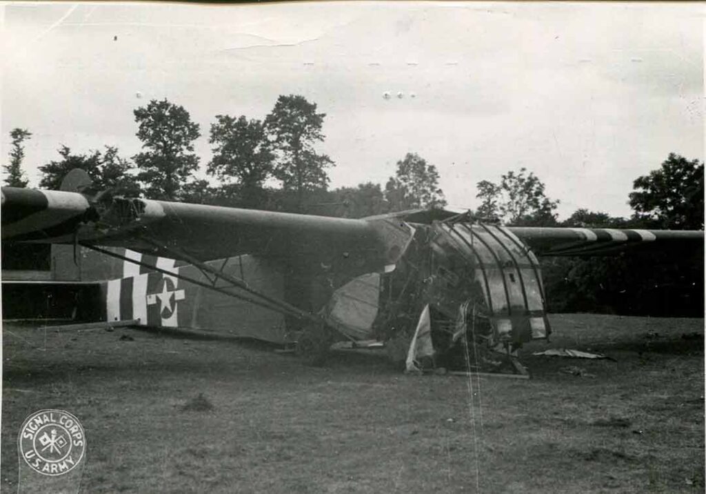 A damaged glider supporting the 82d Airborne Division rests in a field near Sainte-Mère-Église, France, after a rough landing, 12 June 1944. (National Archives)