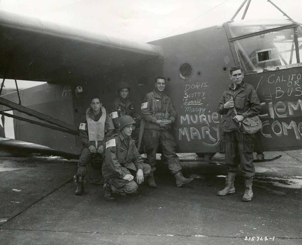 Glider crews who will fly soldiers, equipment, and supplies for the 101st Airborne Division gather for a photograph around a CG-4A before they take off for Holland in Operation MARKET-GARDEN, 18 September 1944. (National Archives)