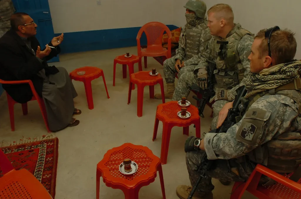 In Qayyarah, Iraq, soldiers of Headquarters and Headquarters Company, 1st Battalion, 175th Infantry (1-175 IN), share tea with a local leader during a patrol near Forward Operating Base Q-West, 23 November 2007. (Photograph by Staff Sergeant Sean McCollum, courtesy of Dvidshub)