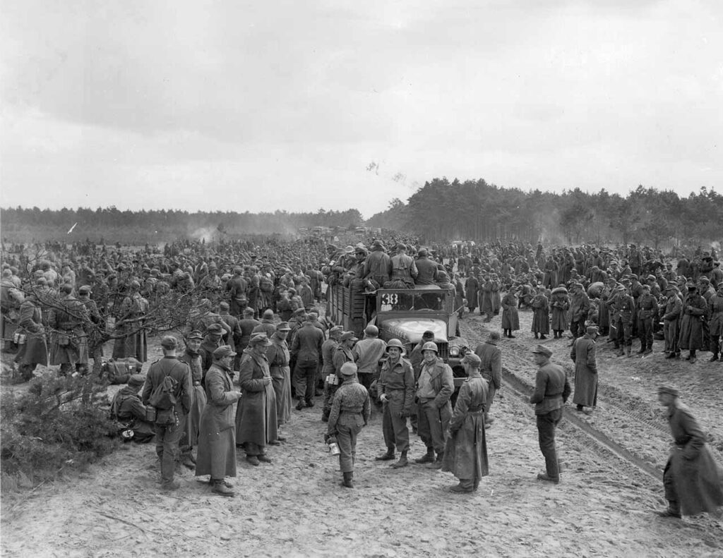 Infantrymen of the 175th Infantry Regiment oversee prisoners of war who surrendered to Allied forces the moment they reached the American side of the Elbe River, at Corleben, Germany, 3 May 1945. (National Archives)