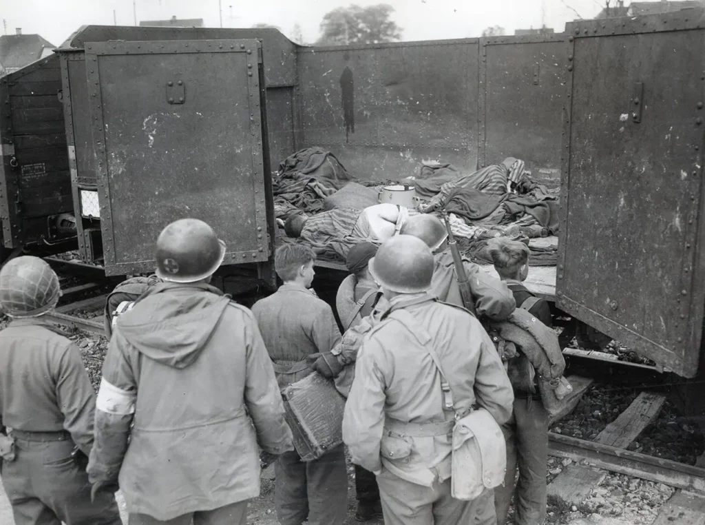 Soldiers of the 45th Infantry Division examine the bodies of prisoners who died in train cars outside of Dachau concentration camp, 29 April 1945. Thirty-nine boxcars containing 2,000 corpses were discovered. (National Archives) 