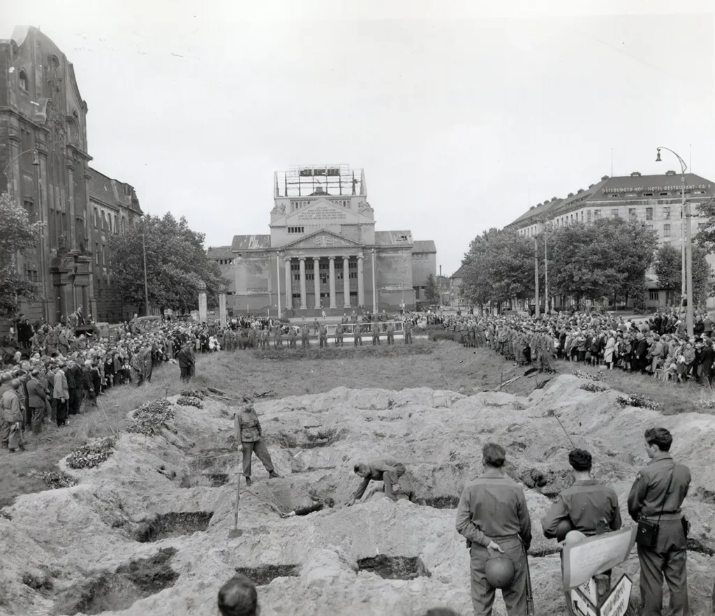 Soviet civilians executed by the Germans and dumped in a mass grave are temporarily reburied on public land in Duisberg. Most of the townspeople were required to attend the funeral and witness what had happened near their homes, 2 June 1945. Similar scenes played out across Europe where concentration camps were discovered. (National Archives) 
