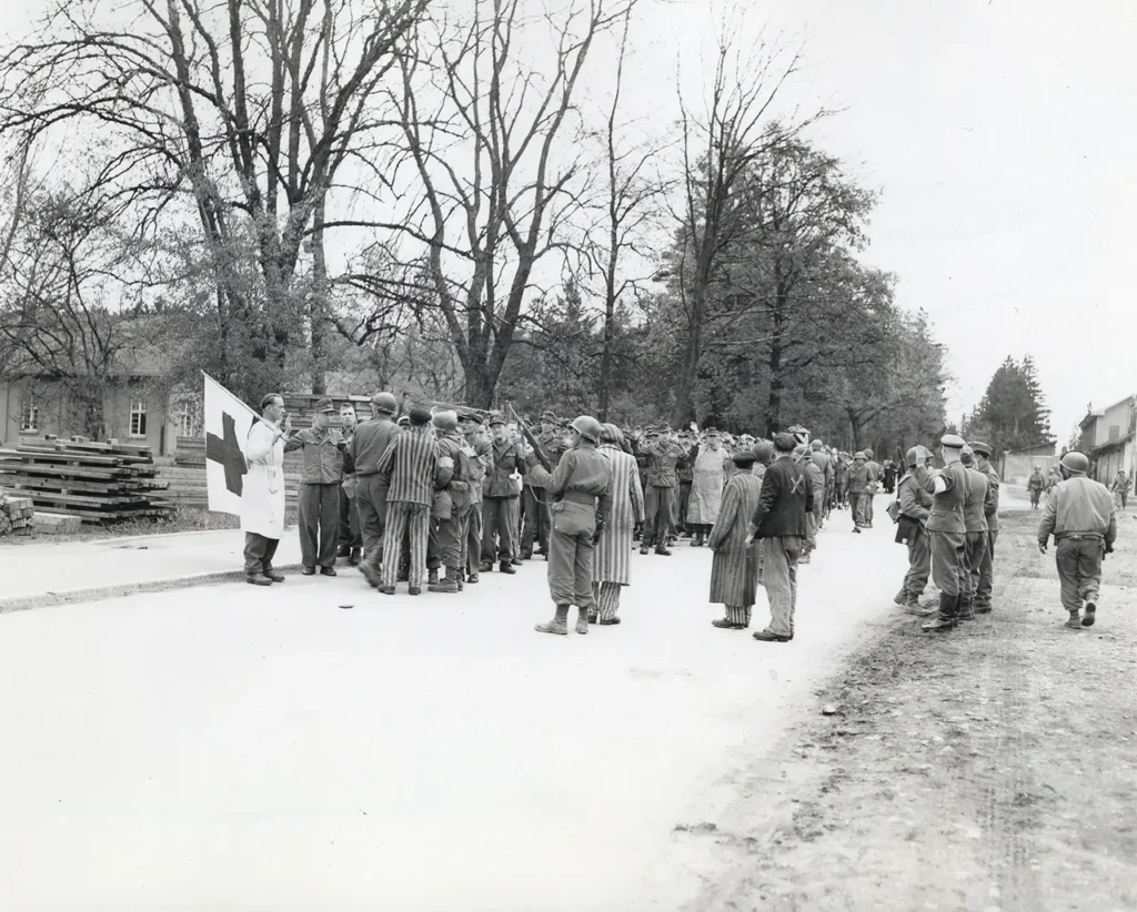 American soldiers accept the surrender of SS guards at Dachau concentration camp, 29 April 1945. Newly liberated prisoners looking on or acting as translators. (National Archives) 