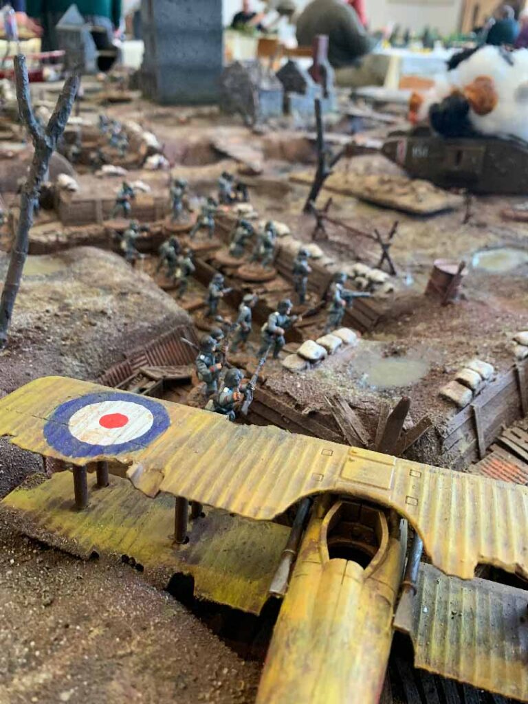 Image is of a miniature landscape resembling a World War I trench and no-man's land. It includes a small plane and Soldier figures.