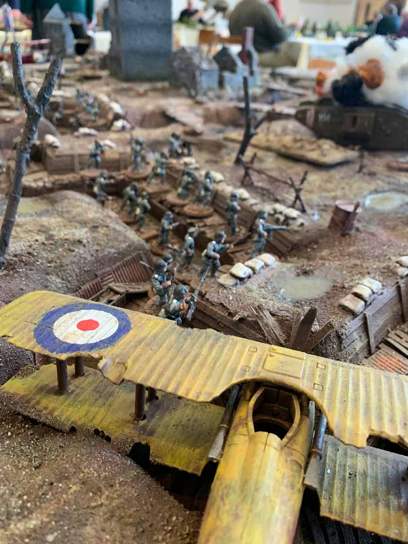 Image is of a miniature landscape resembling a World War I trench and no-man's land. It includes a small plane and Soldier figures.